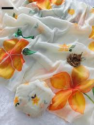 floral chiffon fabric with an orange hibiscus and green leaf print pattern.