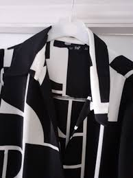 black-and-white geometric print blouse features a sharp collar and a distinctive lace-up front tie detail.