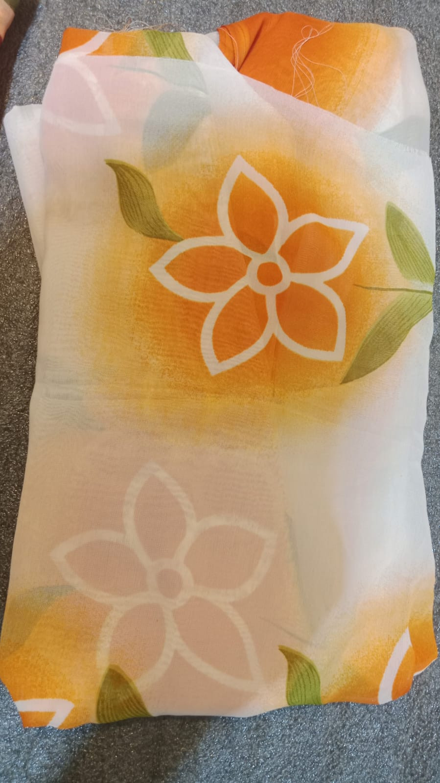 floral chiffon fabric with an orange hibiscus and green leaf print pattern.